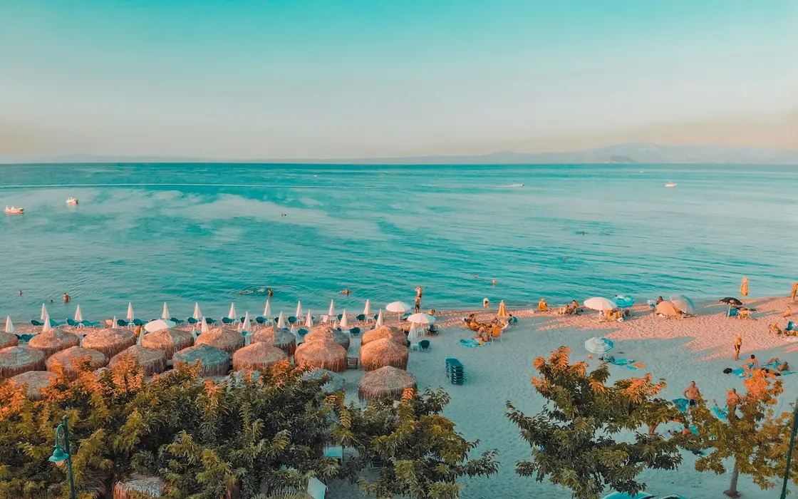 Pefkochori Strand auf Kassandra mit Sonnenschirmen und blauem Meer im Abendlicht